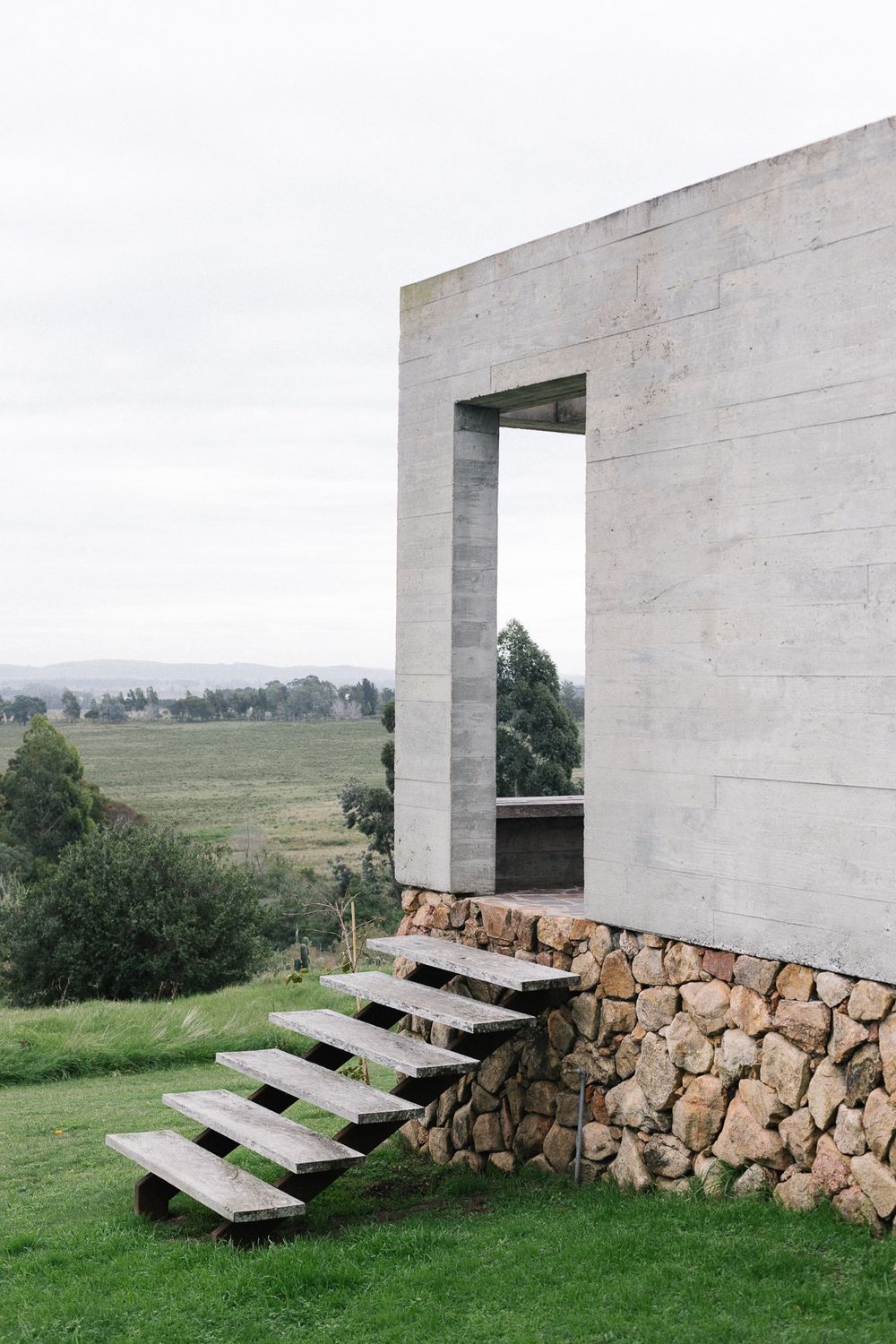 Contemporary architectural building perched on a rocky hillside with natural landscape surroundings.