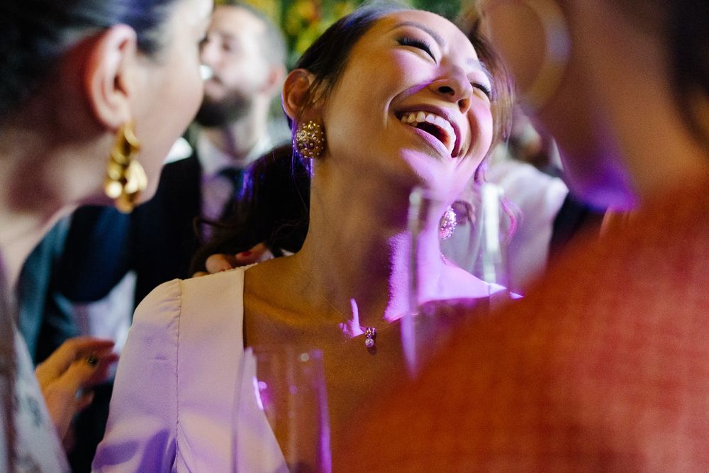 Candid moment of pure joy and laughter at a wedding reception with purple lighting.
