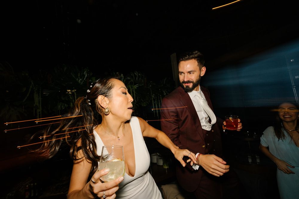 Candid reception moment showing celebration with drinks in warm lighting.