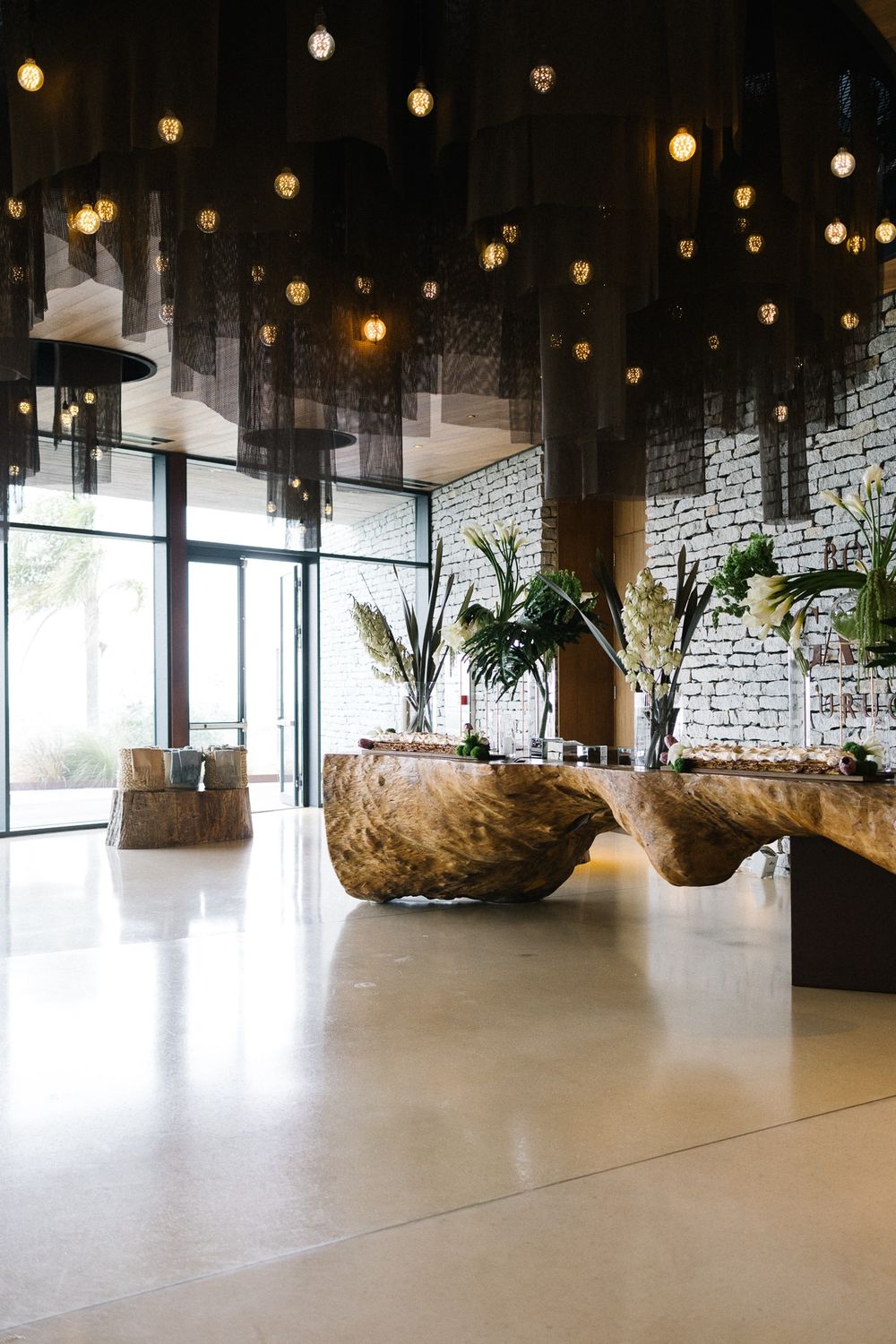 Modern venue interior with hanging lights and natural stone planters.