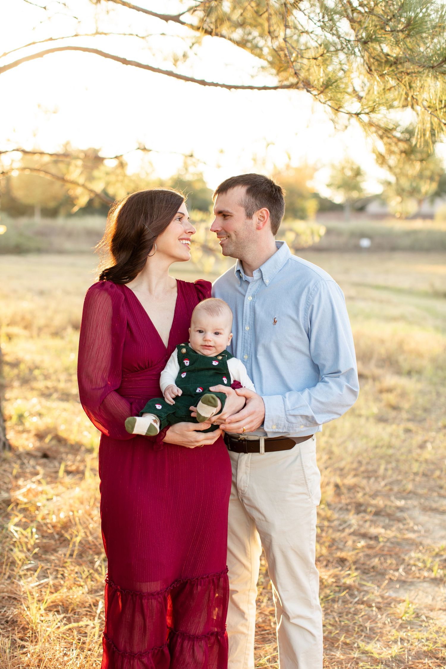 Golden hour family photo with burgundy dress against warm autumn background.