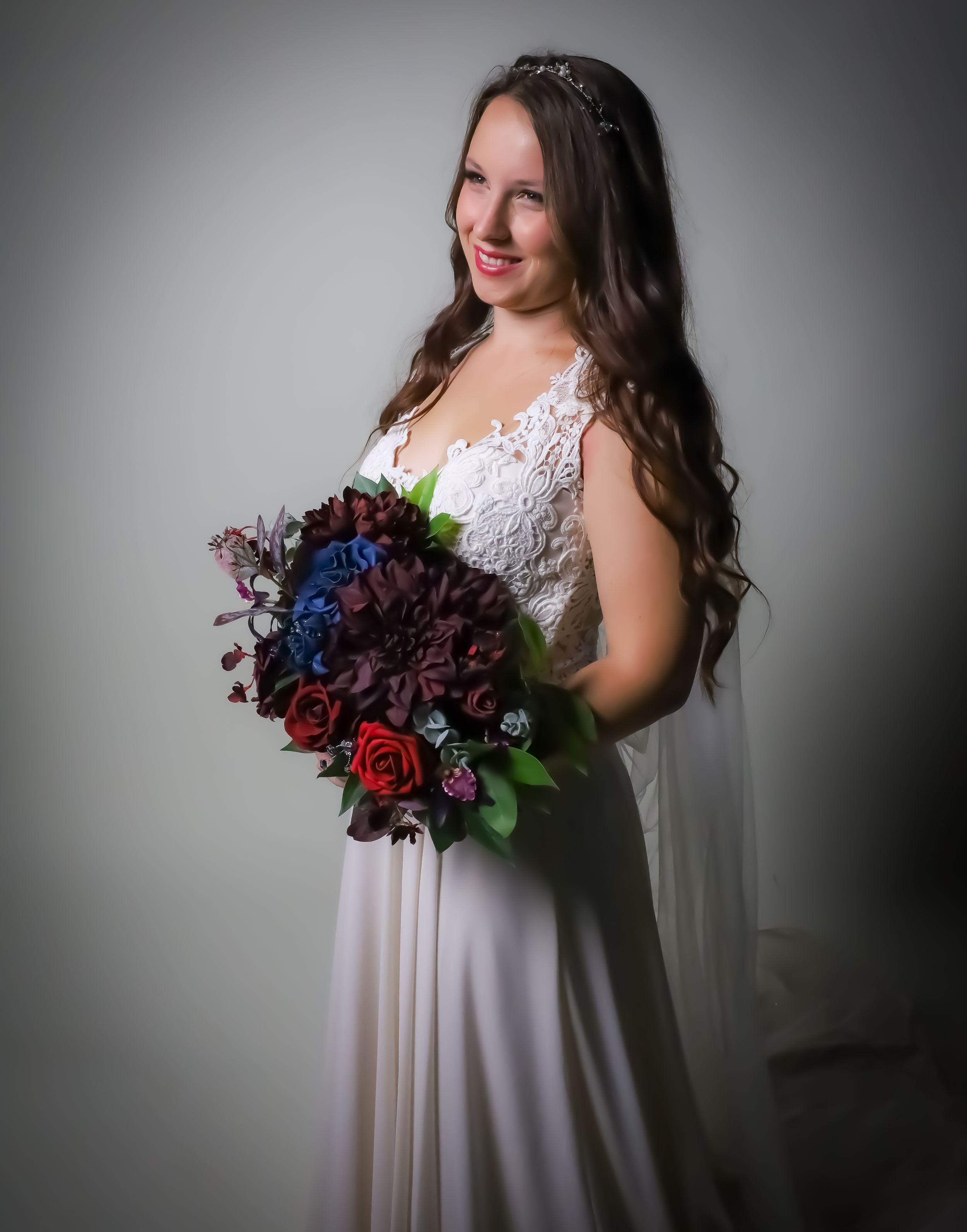 Studio bridal portrait with dark moody lighting and deep purple floral bouquet.