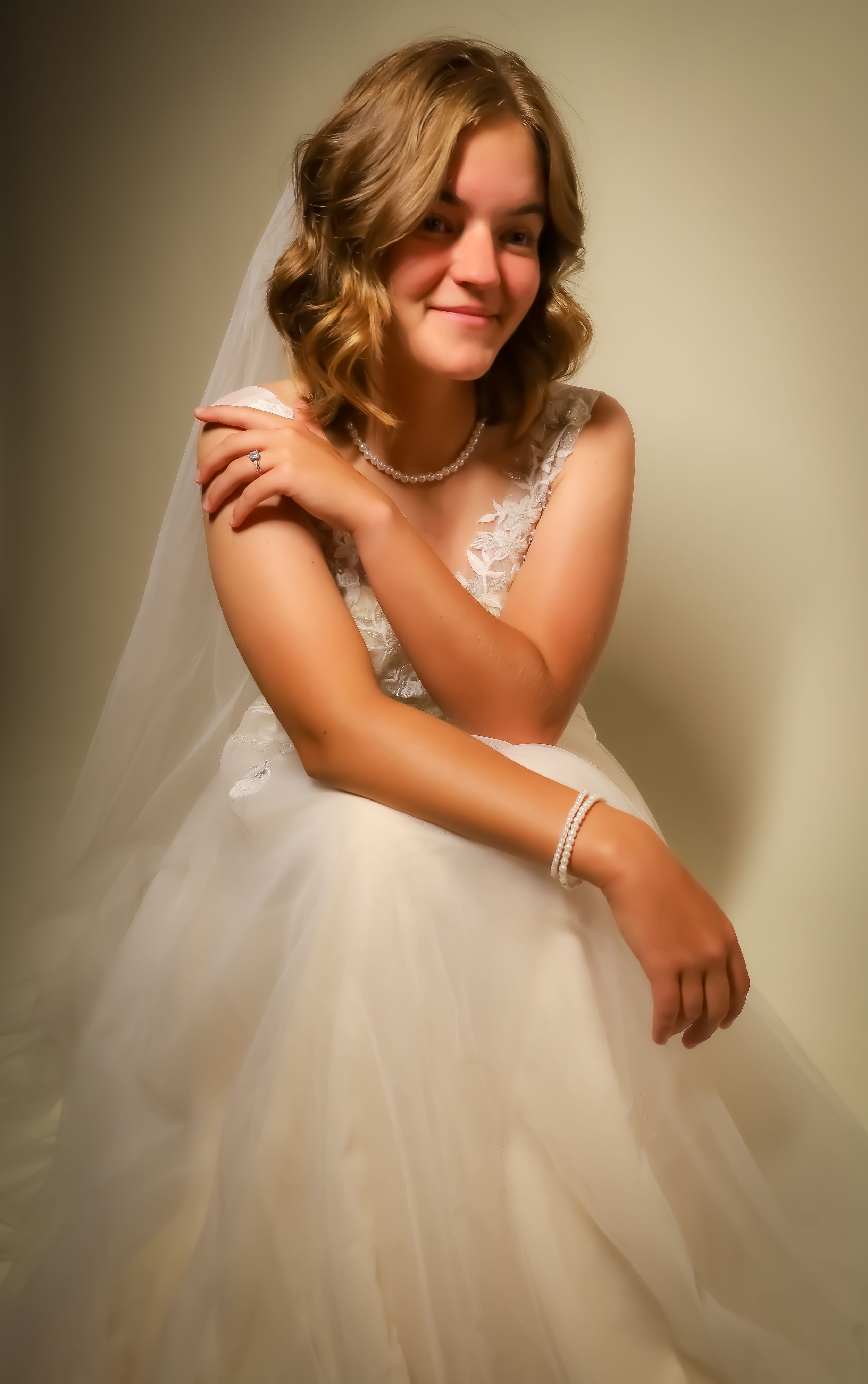 Artistic sequence of a bride in a white lace dress sitting gracefully against a warm backdrop.