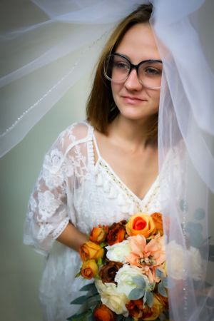 Bridal portrait series showing delicate veil and orange and white bouquet details.