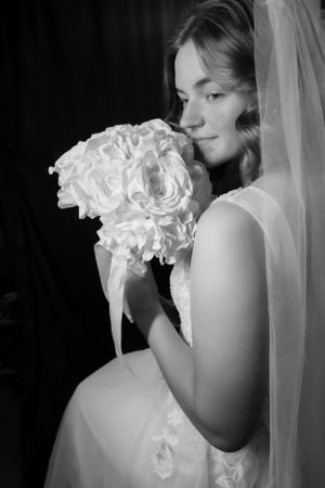 A bridal portrait series showing delicate white roses held against a dark background.
