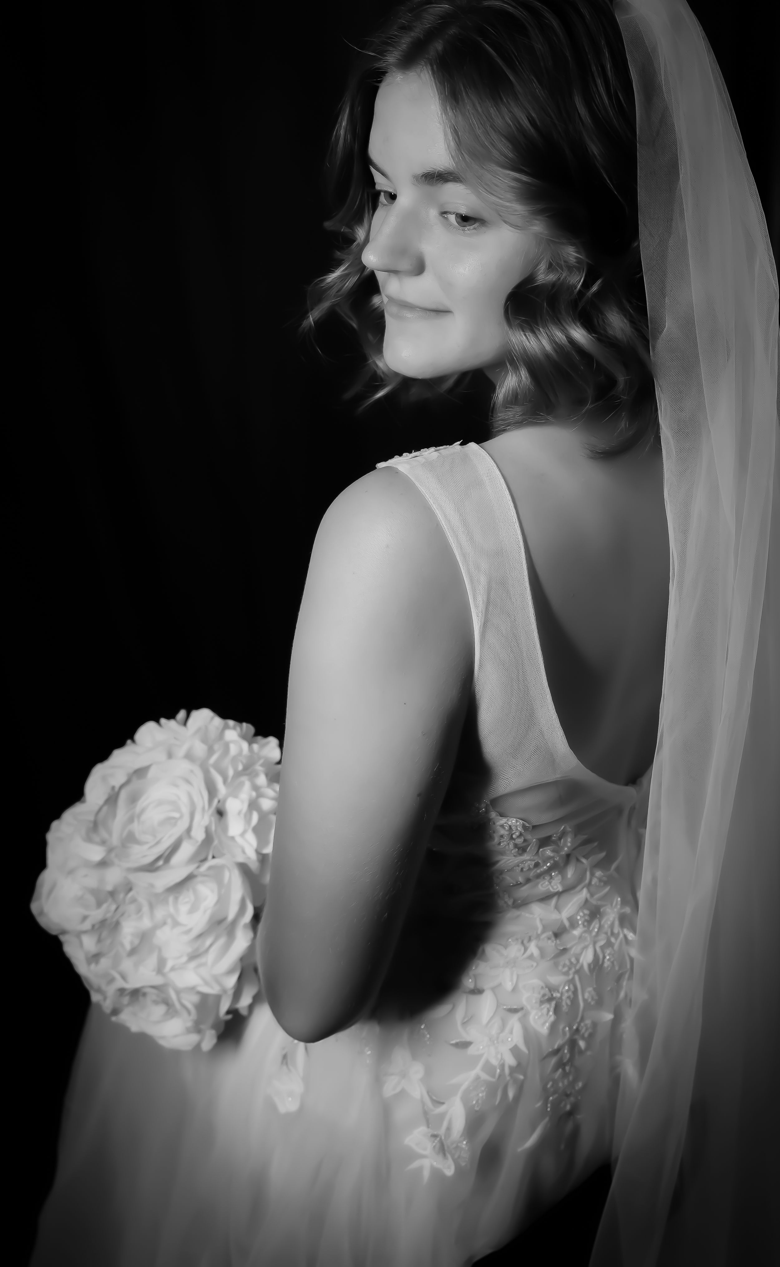 Black and white bridal portrait captures ethereal details of lace dress and veil.