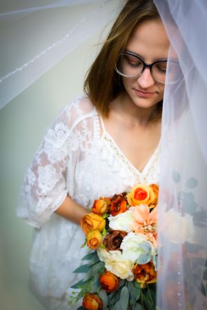Close-up bridal portraits with white lace dress and vibrant orange and cream bouquet.