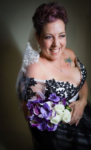 Elegant bridal portrait featuring black dress with purple and white floral details.