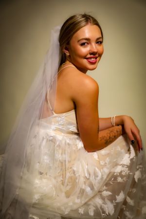 Joyful bride poses in flowing white wedding dress with delicate lace details.