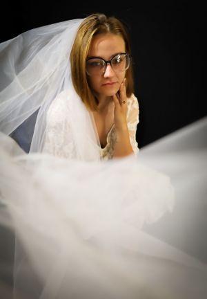 Artistic bridal portraits with flowing white veil against dark background.