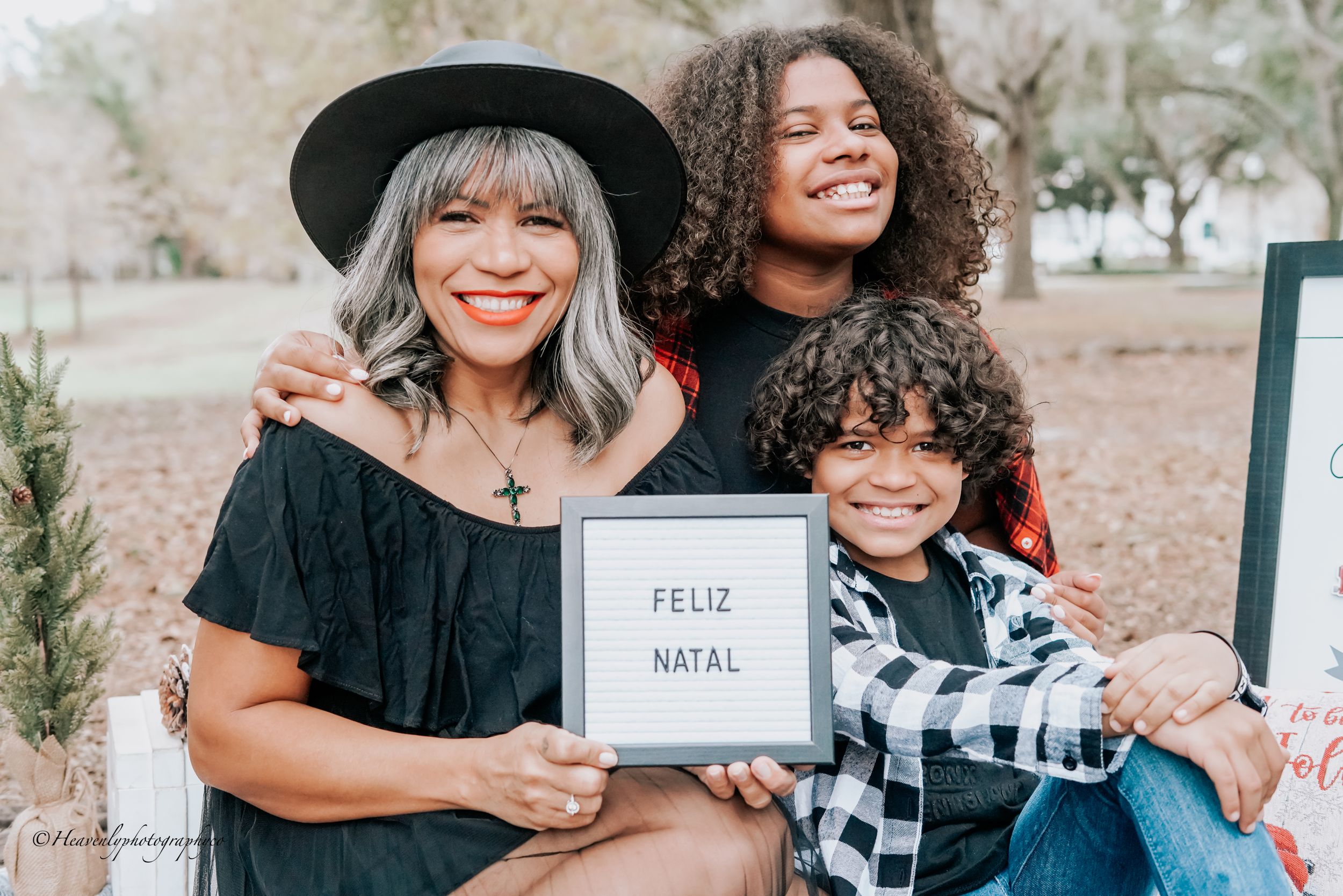 Festive holiday photo session with plaid shirts and decorative signs on a blanket outdoors.
