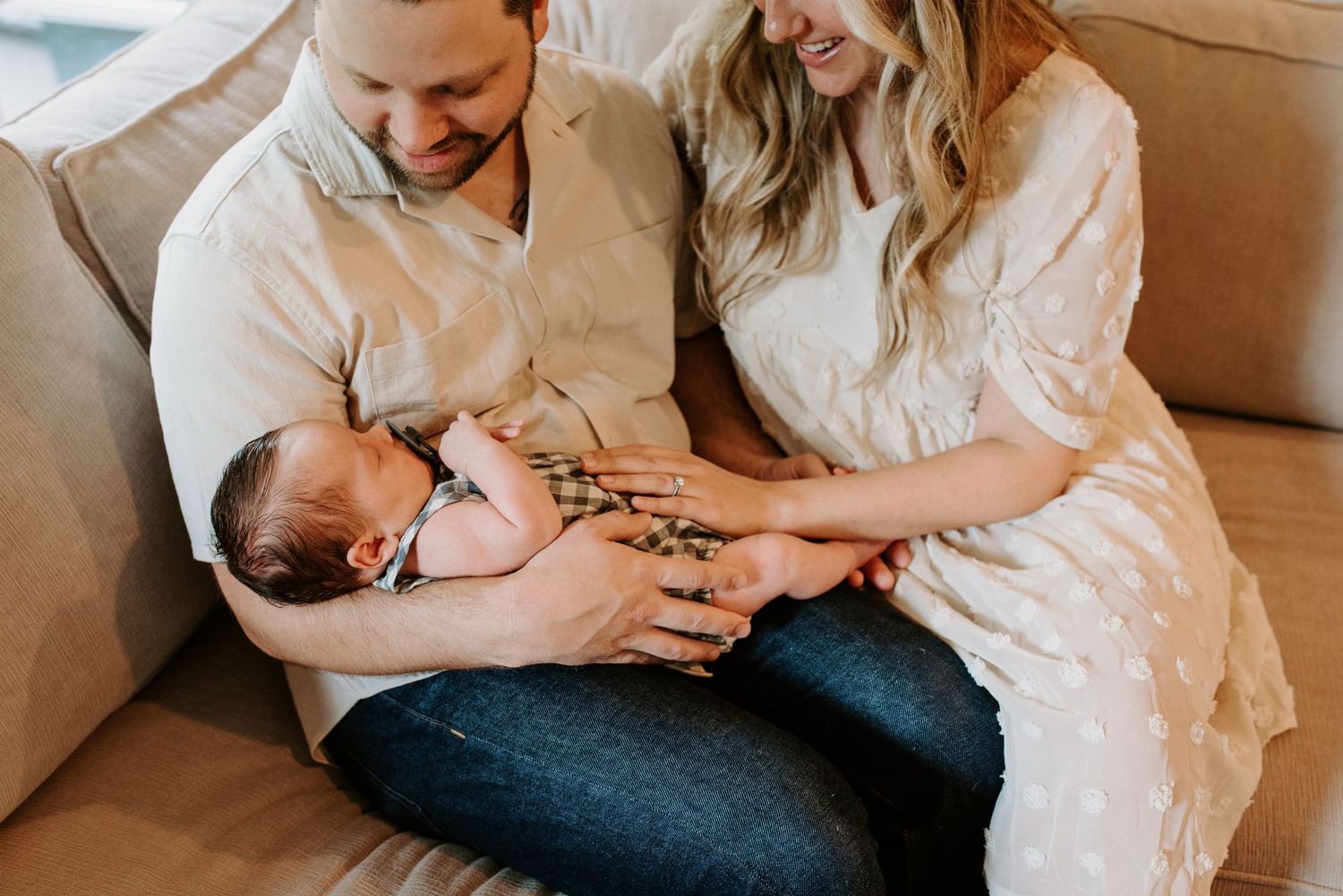 Loving family moment on beige couch with newborn baby.
