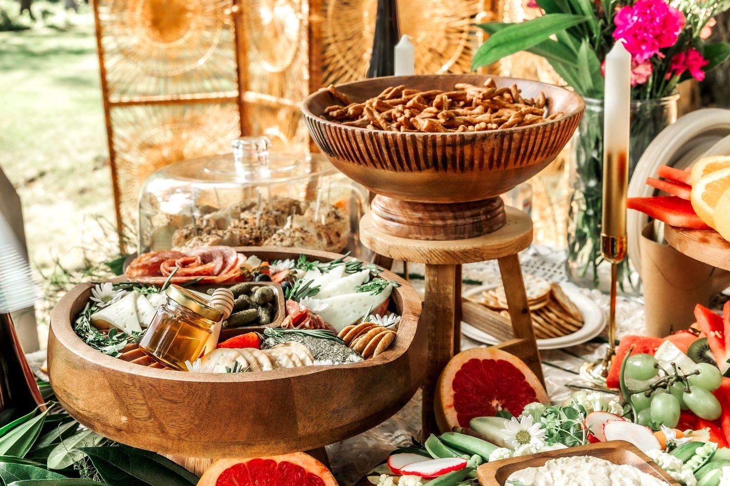 Elegant food display table with citrus fruits and appetizers arranged on rustic wooden platters.