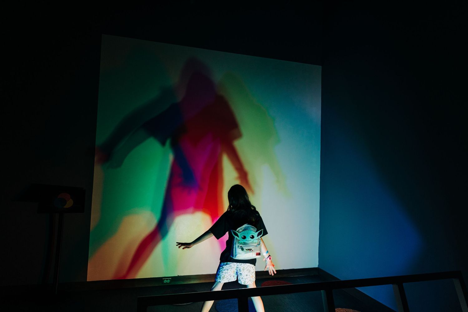 girl standing in front of colorful lights casting a shadow at Monroe Science Center
