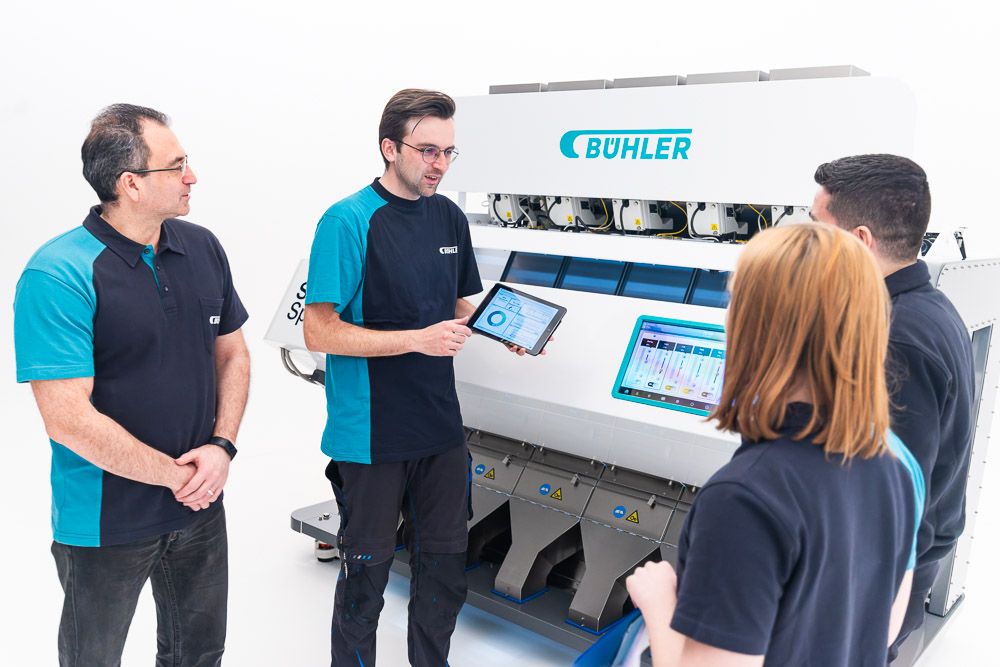 Engineering team gathered around advanced optical sorting machinery during a commercial photography shoot.
