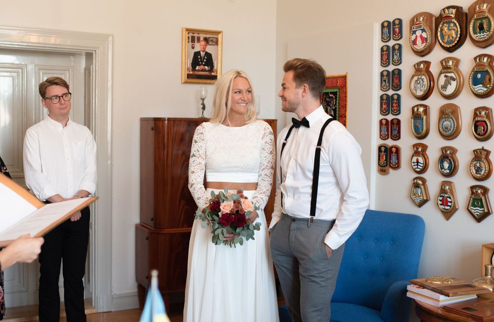 A wedding ceremony in progress inside a room decorated with wall plaques and classic decor.