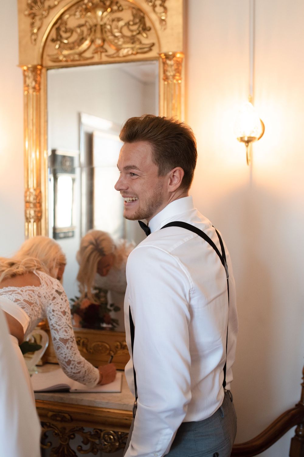 Elegant wedding preparation scene with ornate gold mirror and warm lighting.