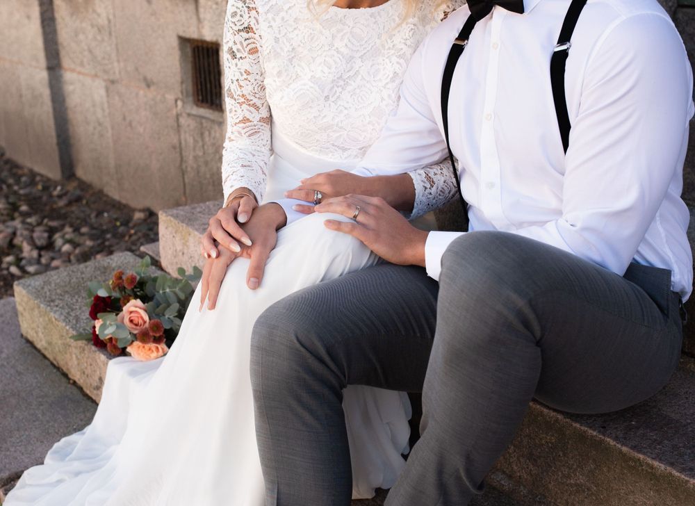 A close-up of wedding attire details with delicate lace and suspenders while sitting outdoors.