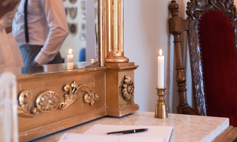 An ornate golden mirror frame with lit candles and a pen on a registration table.