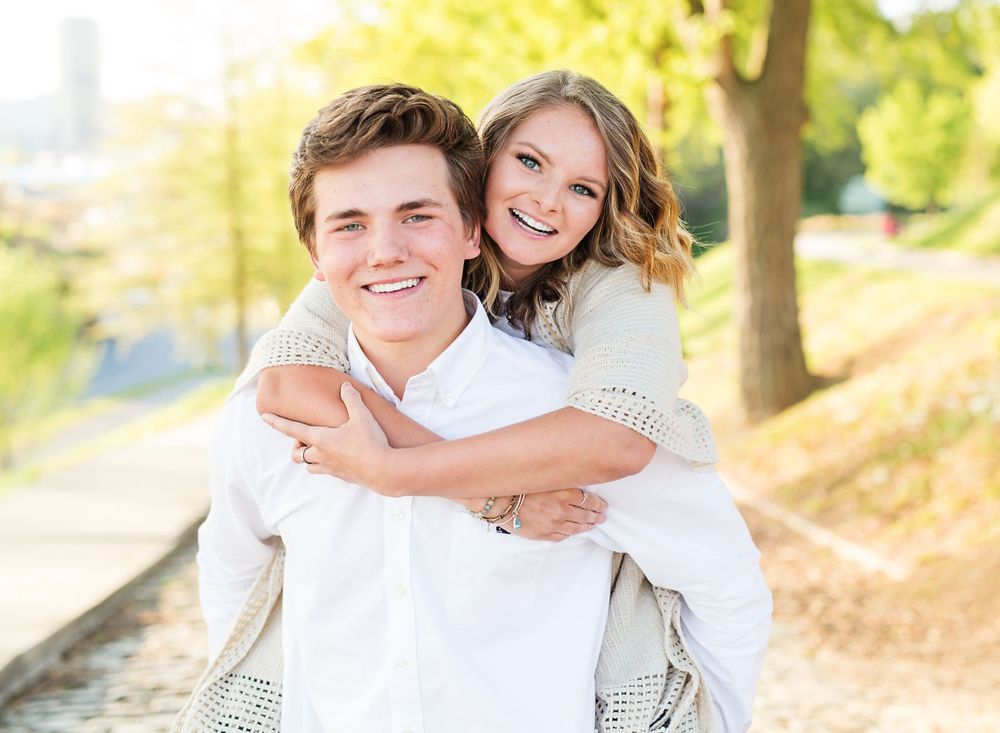 A couple shares a joyful embrace outdoors on a sunny autumn afternoon.