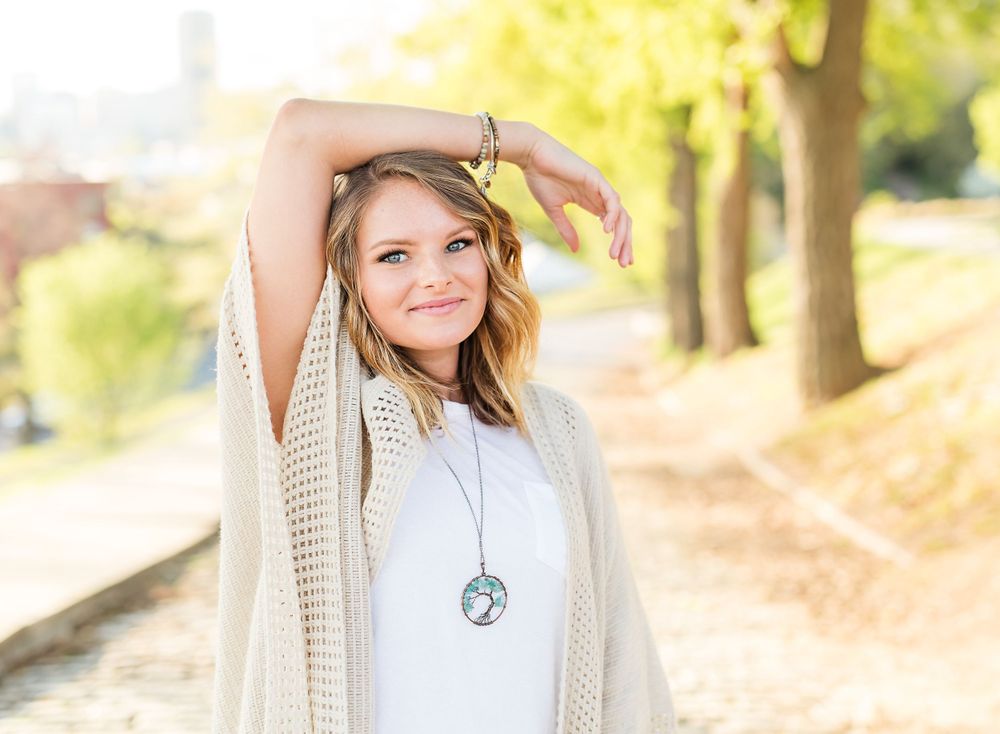 A person poses playfully while wearing a flowing cream cardigan outdoors.