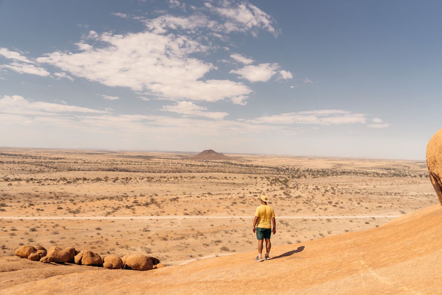 homme de dos devant un paysage désertique de spitzkoppe