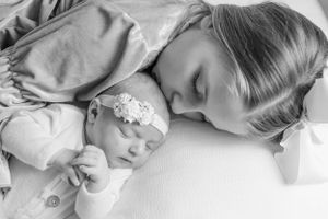 A tender black and white photograph of two sleeping figures with a delicate headband detail.