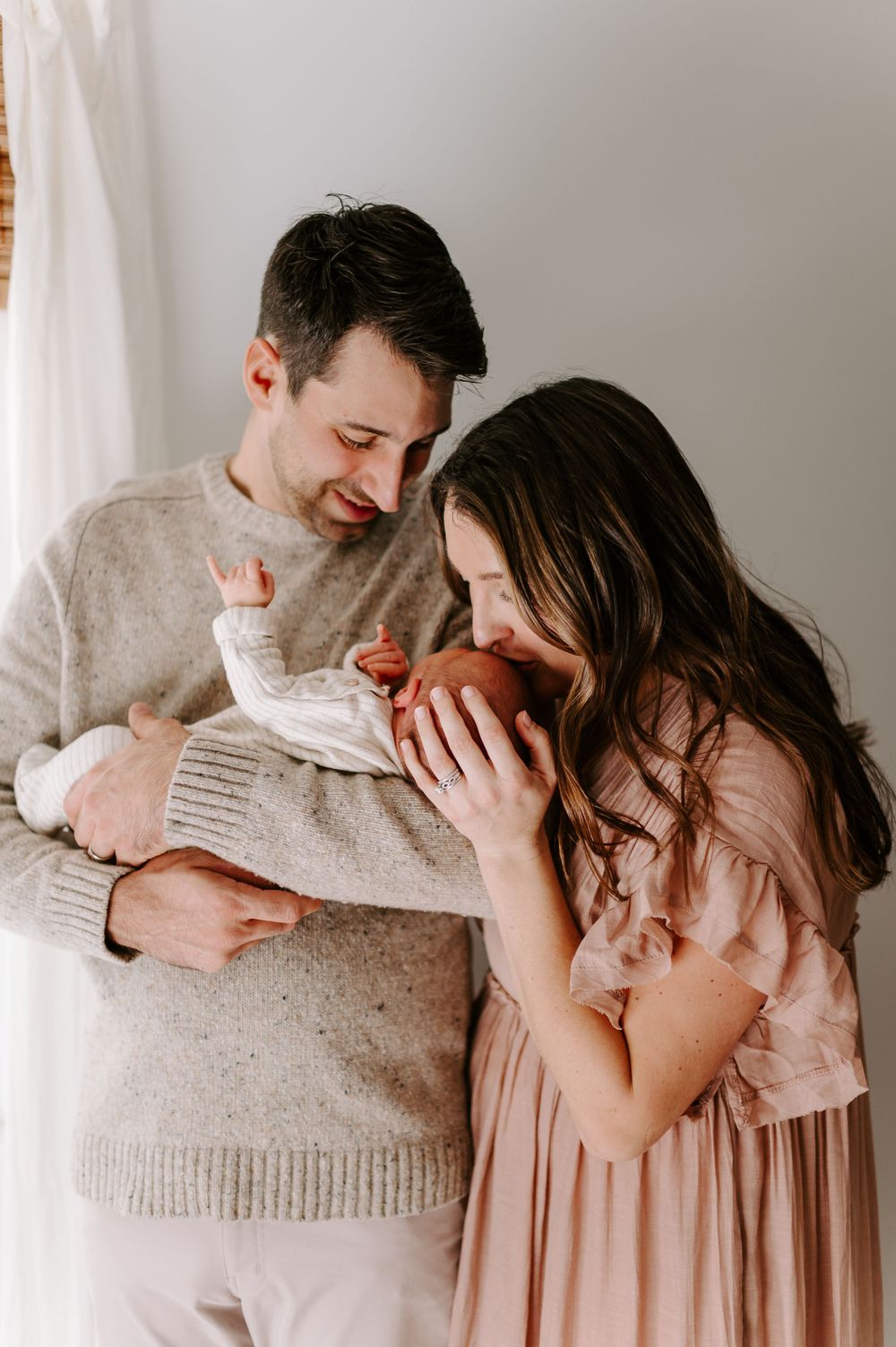 An intimate indoor photo with soft lighting and people in neutral-toned clothing.
