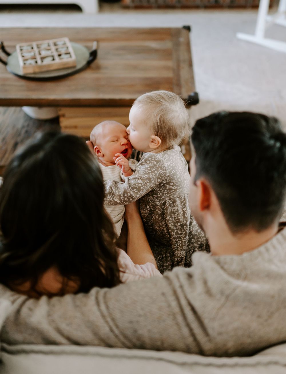 A cozy indoor family scene with people lounging together on a grey couch.