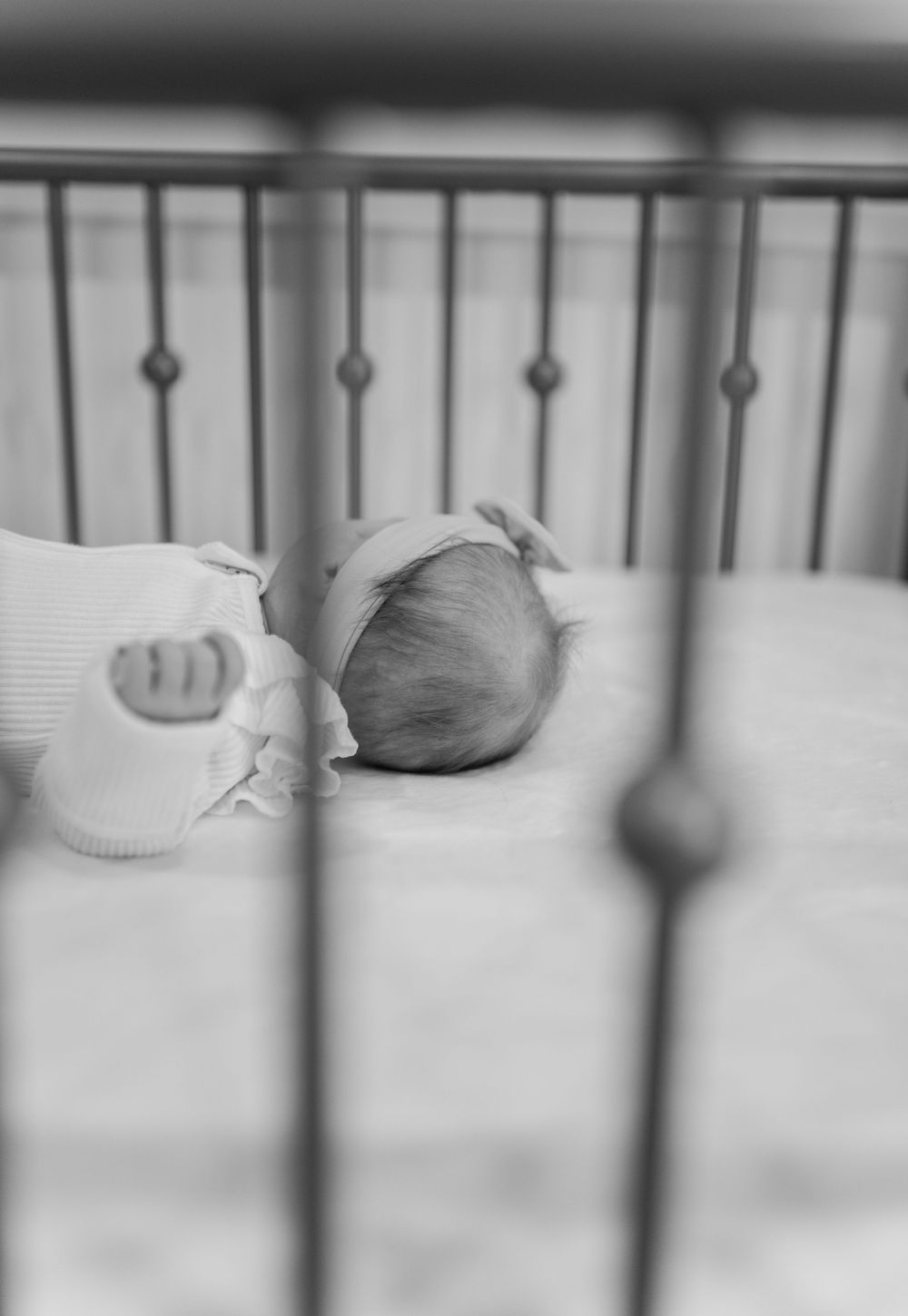 Close-up view of white crib railings and bedding in nursery.