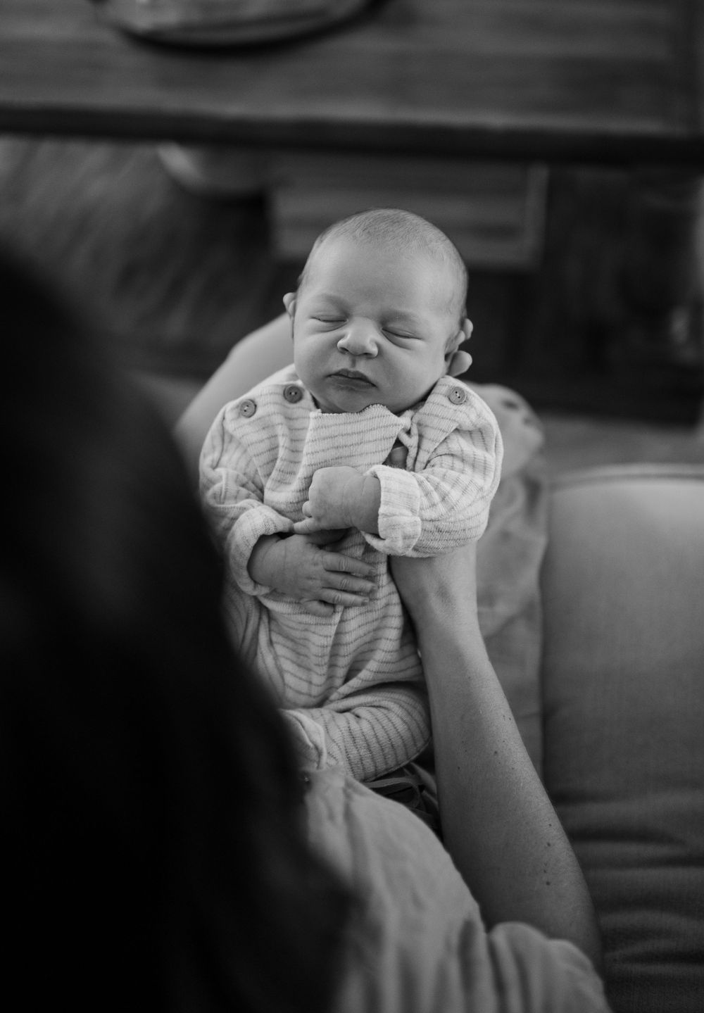 A black and white close-up photo of a baby being held and fed.