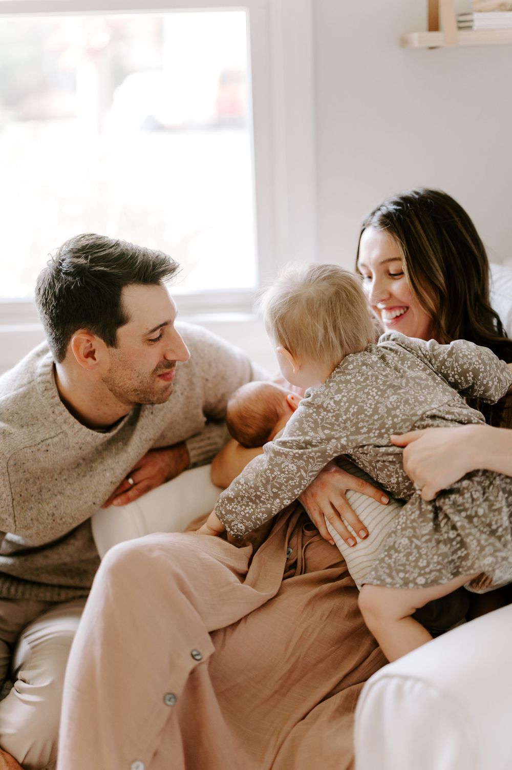 Loving family cuddles together on comfortable couch during intimate photoshoot.