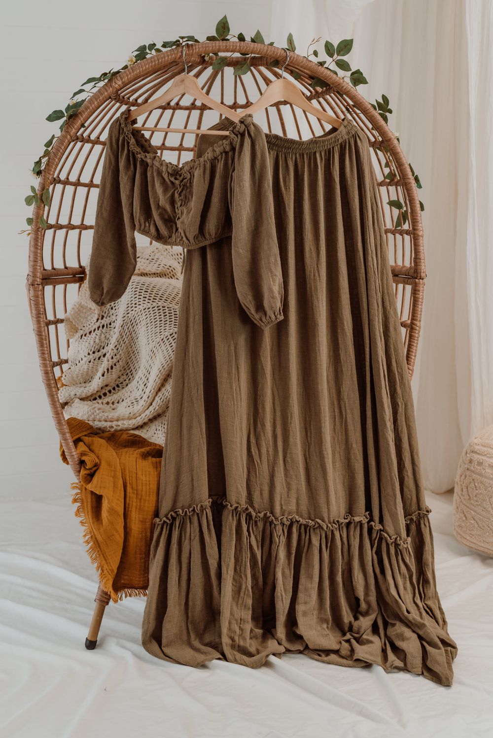 Brown bohemian maxi dress with ruffled hem displayed on decorative rattan peacock chair.