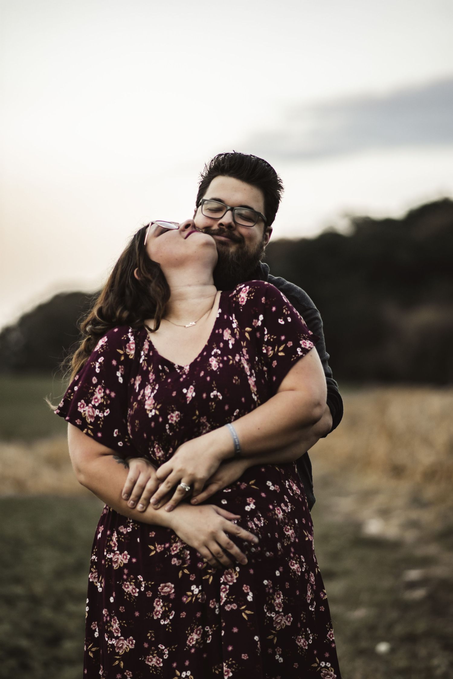 Couple sharing a loving embrace in an outdoor setting with golden hour lighting.