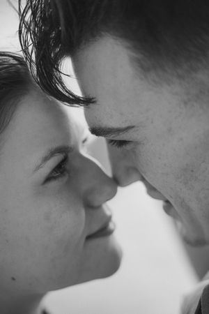 Black and white close-up of a romantic couple facing each other, almost kissing, with tender expressions.