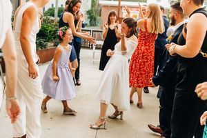 Wedding guests dancing and celebrating on white floor during reception.