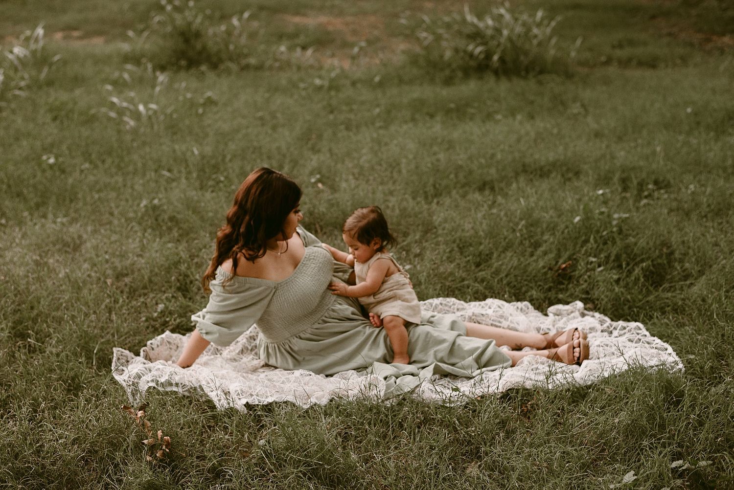 A peaceful scene of two people relaxing on a white blanket in a grassy field.