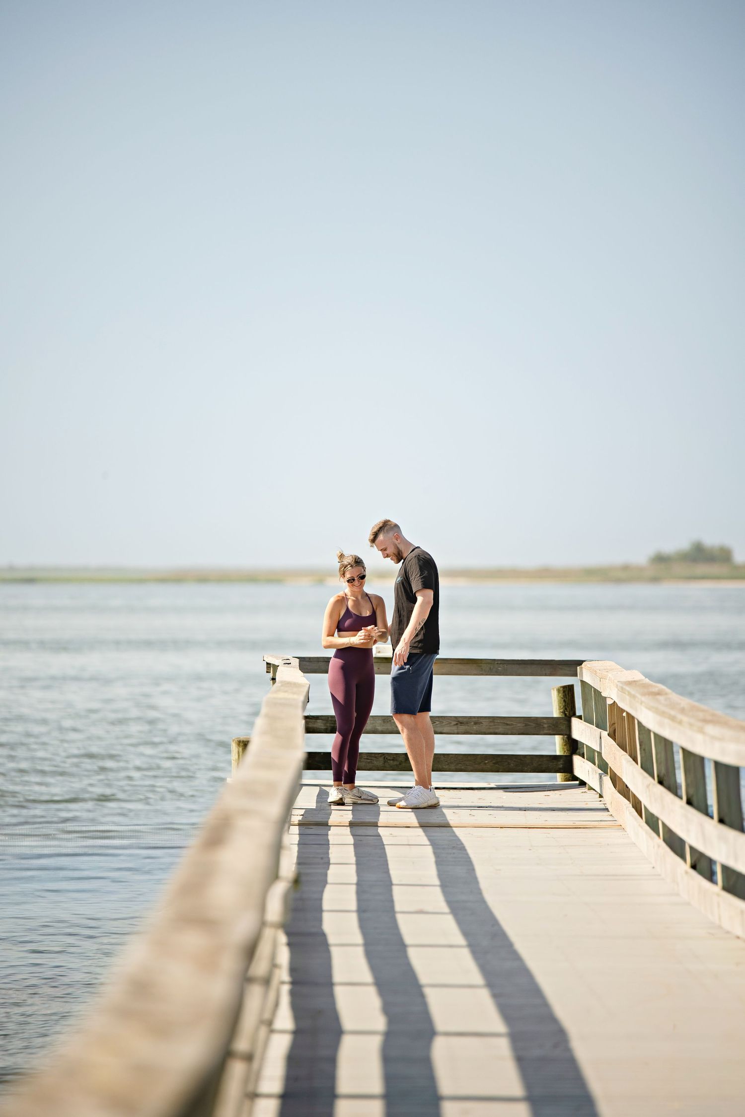 A romantic proposal scene set between rows of grapevines in a scenic vineyard with white flowers and a blanket.