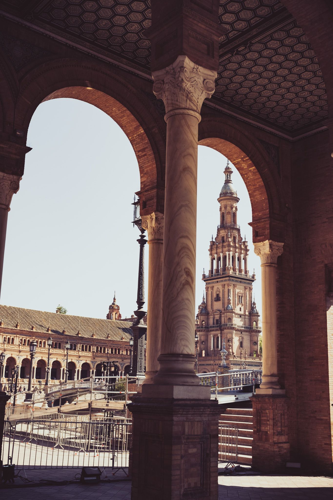 View through stone arches of ornate tower at Plaza de Espana Seville Spain in warm sunlight.