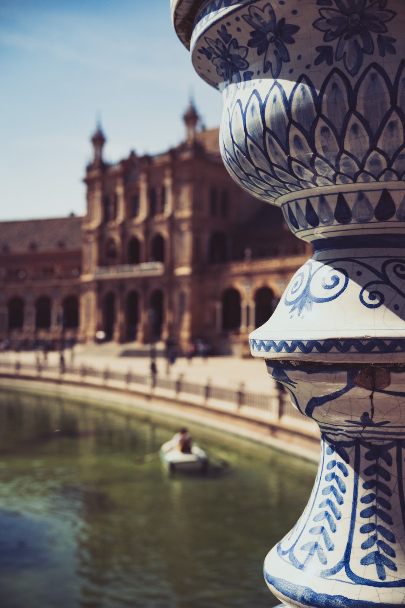 Close-up of decorative blue and white ceramic balustrade at Plaza de Espana Seville with canal behind.