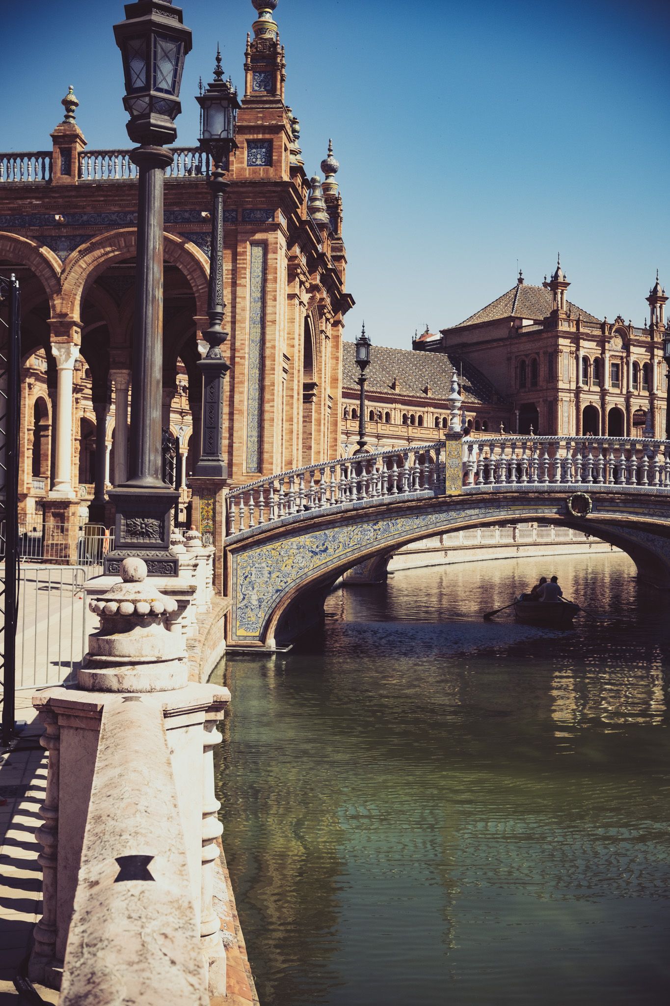 Ornate bridge over canal at Plaza de Espana Seville Spain with decorative lamp posts and balustrades.
