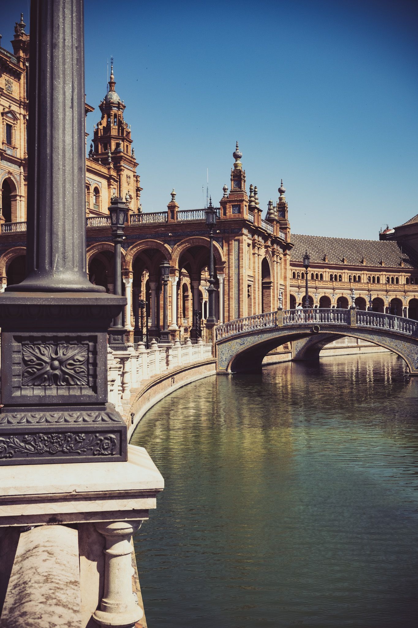 Decorative iron lamp post and ornate bridge over canal at Plaza de Espana Seville Spain.