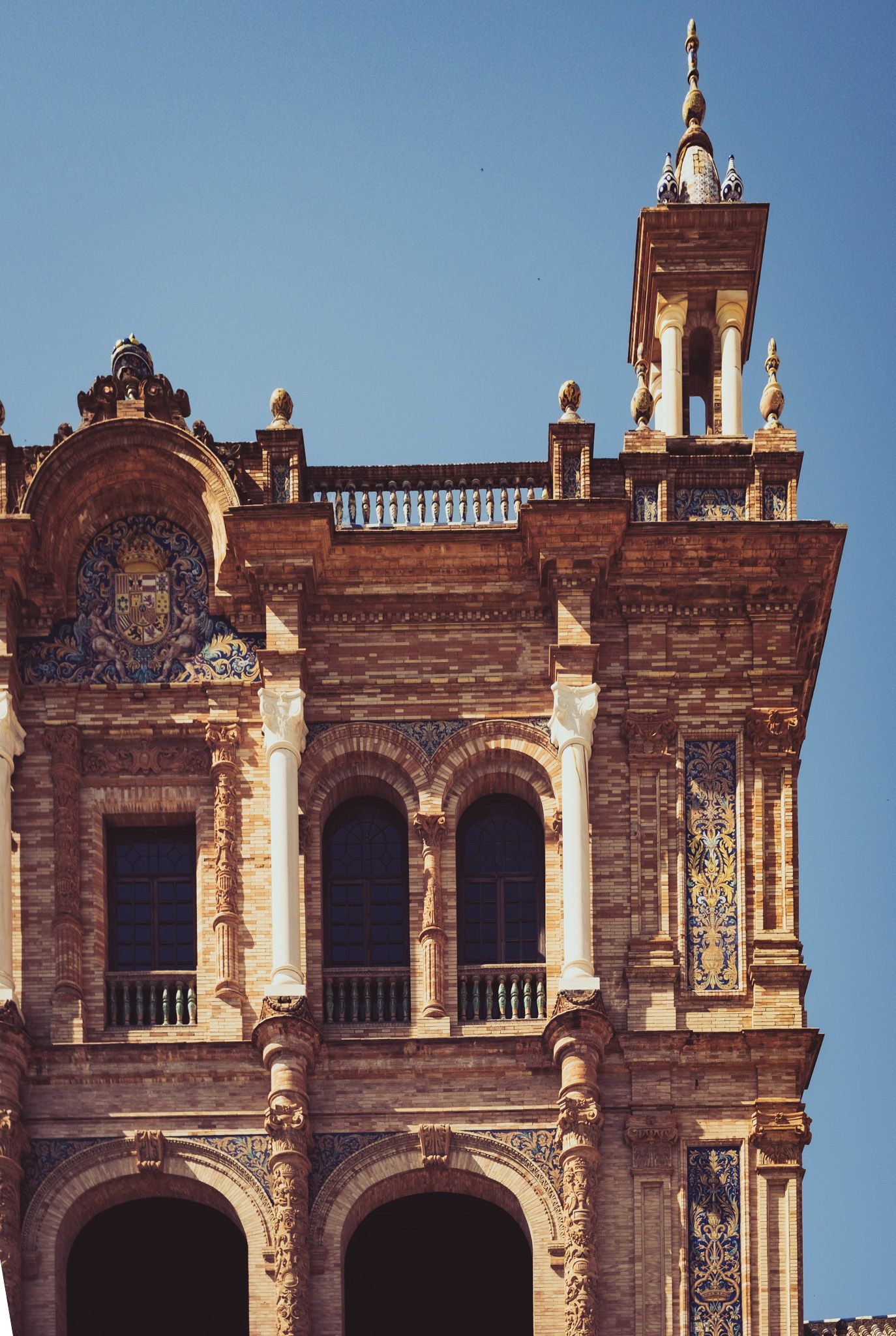 Detailed Renaissance baroque facade of Plaza de España building in Seville, Spain, with ornate carvings and arched windows.