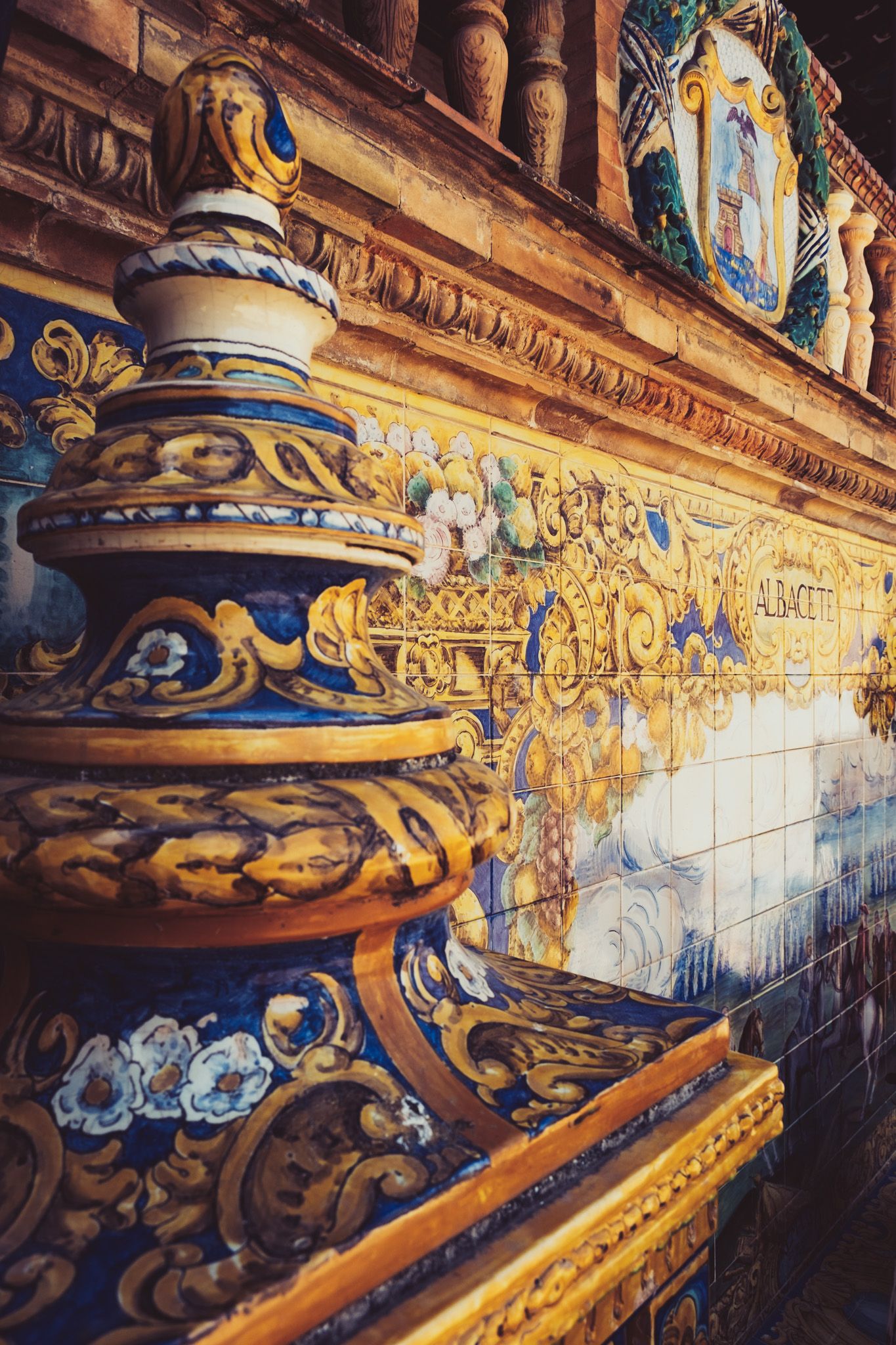 Intricate golden and blue azulejo ceramic tile alcove decoration at Plaza de España in Seville, Spain.