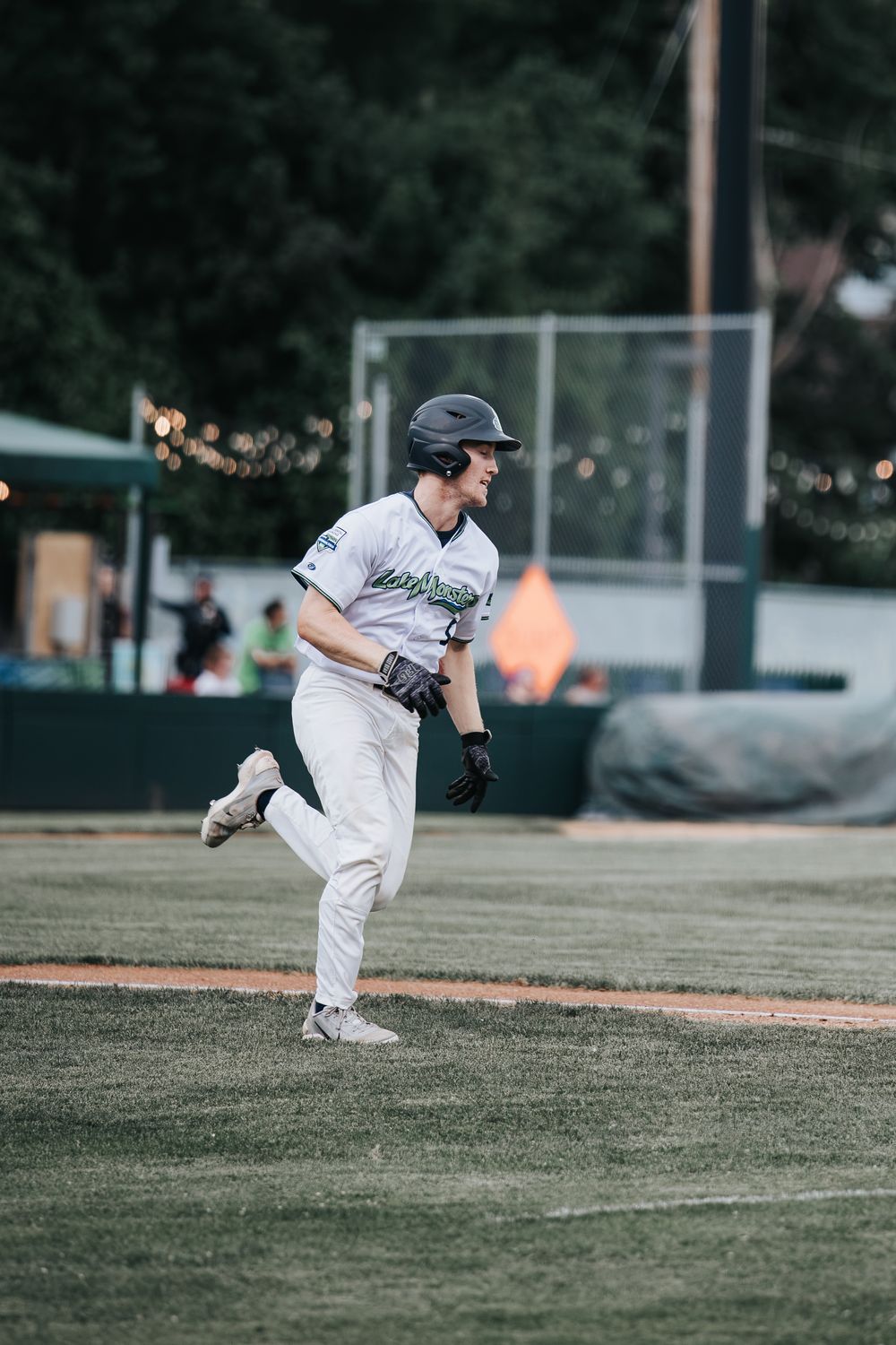 Baseball player in white uniform sprinting on the field during an evening game.