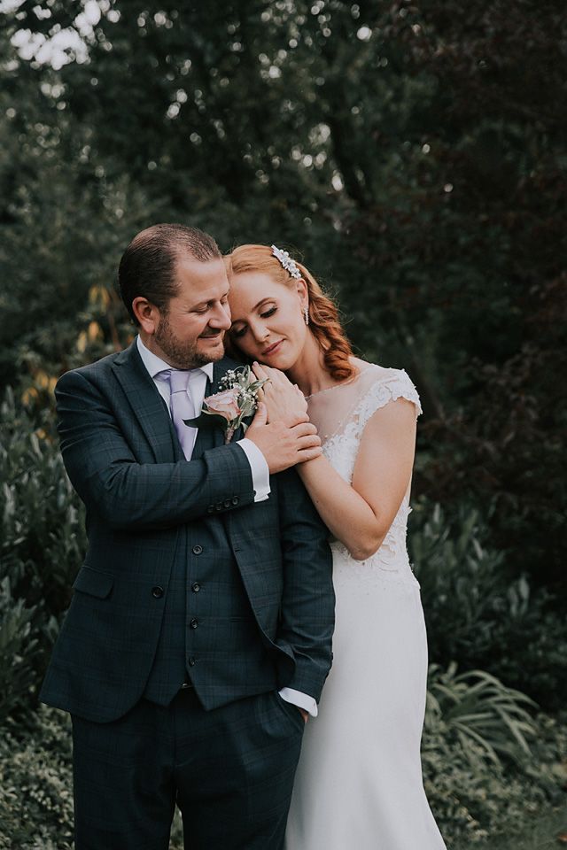 bride lovingly resting on grooms shoulder on the beautiful gardens of langtons house registry office in Hornchurch