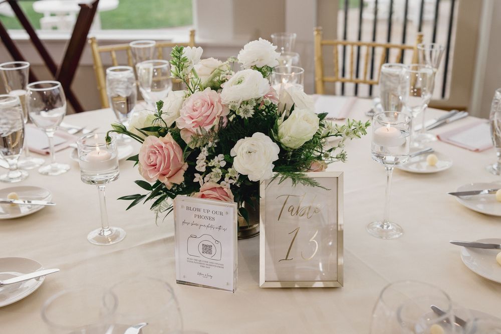 Elegant wedding table centerpiece with pink and white roses beside a gold table number frame. OceanCliff Hotel in Newport, Rhode Island.