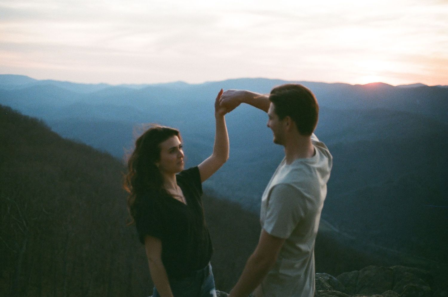 Couple dancing together at sunset with mountain vista backdrop.
