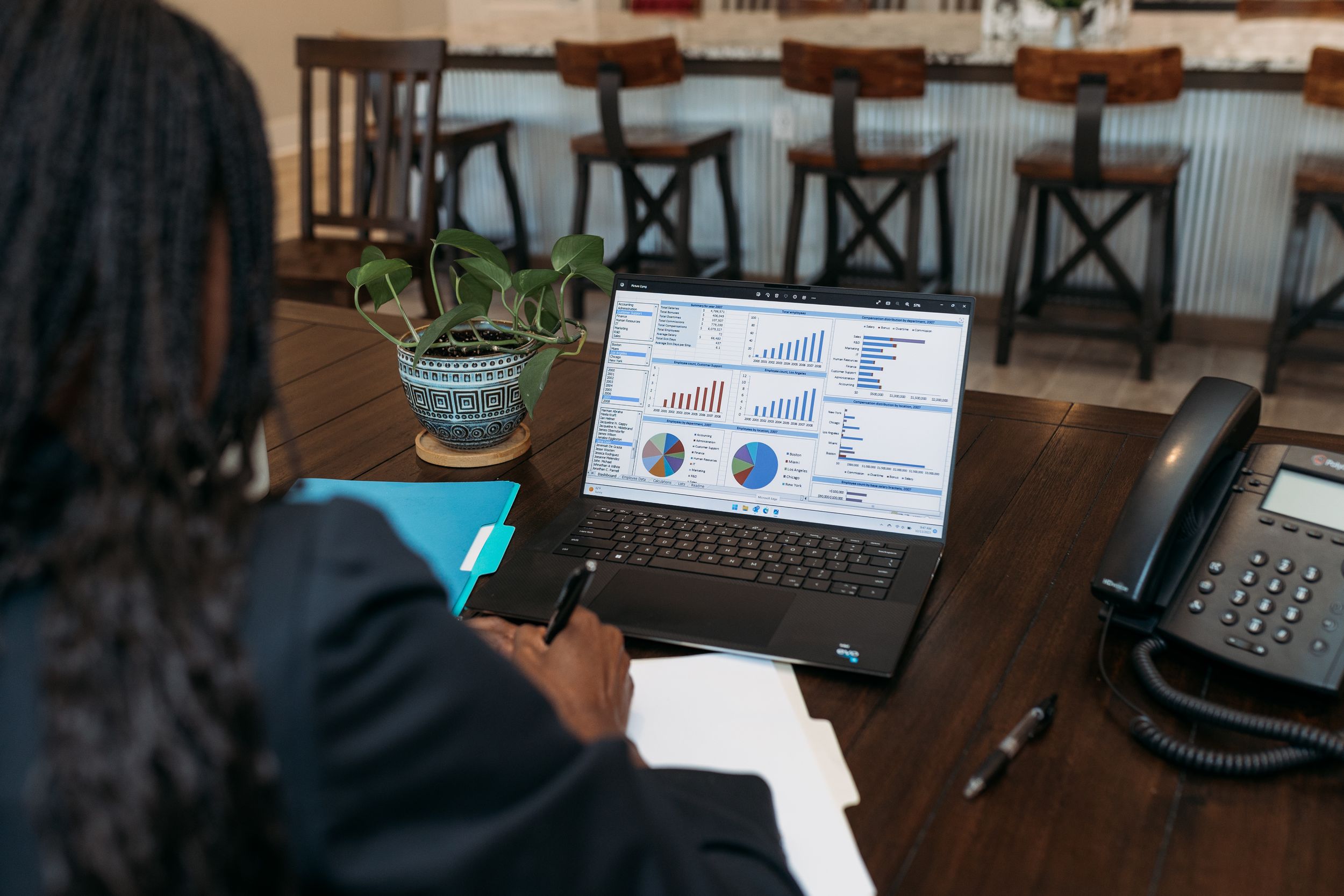 Professional woman analyzing business charts and graphs on a laptop computer at a conference table.