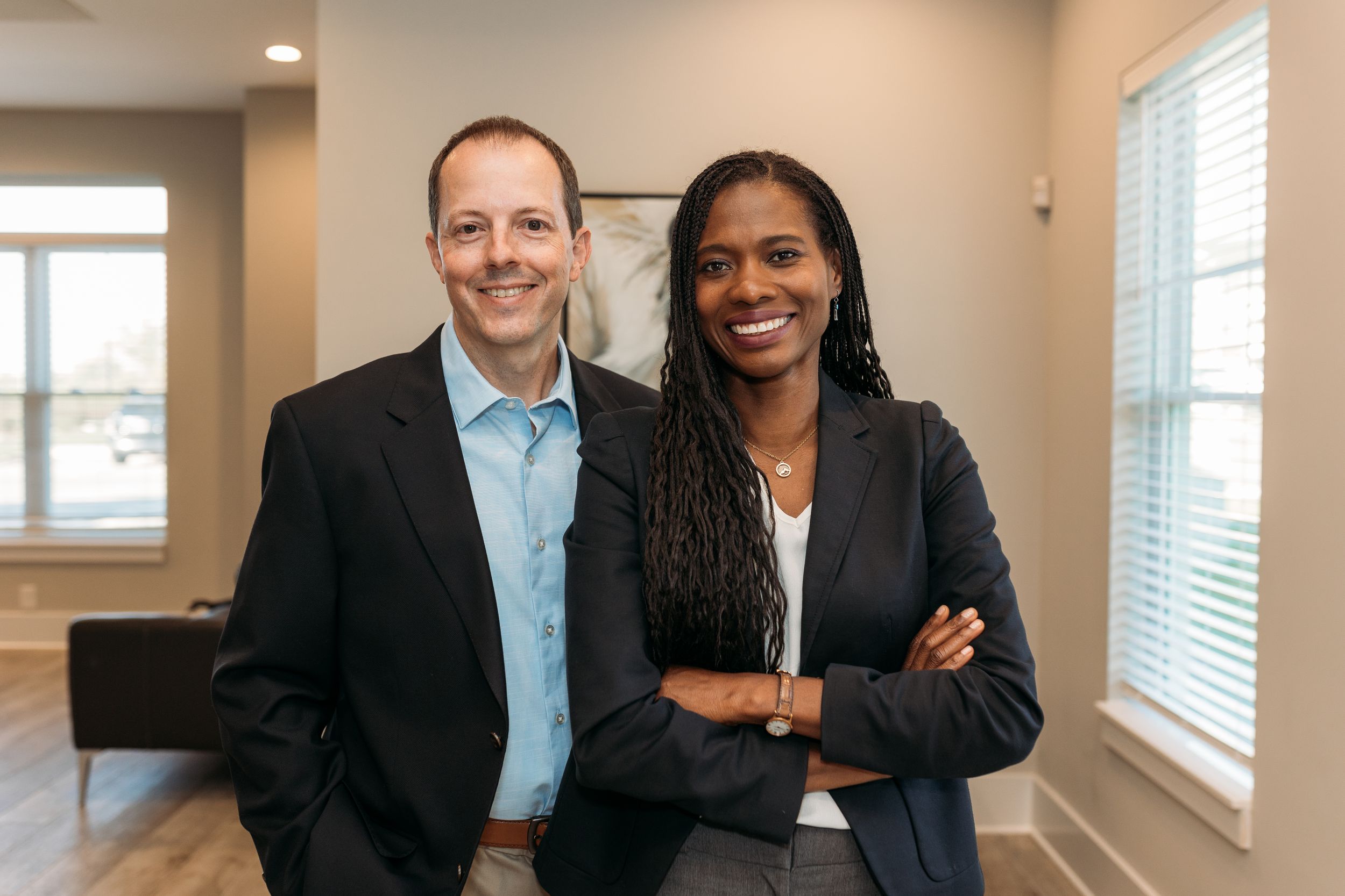 Two professional real estate agents smiling together in a modern home interior.